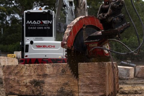 Excavator-mounted rock saw cutting a 2 m A-grade sandstone block on site in Kenthurst