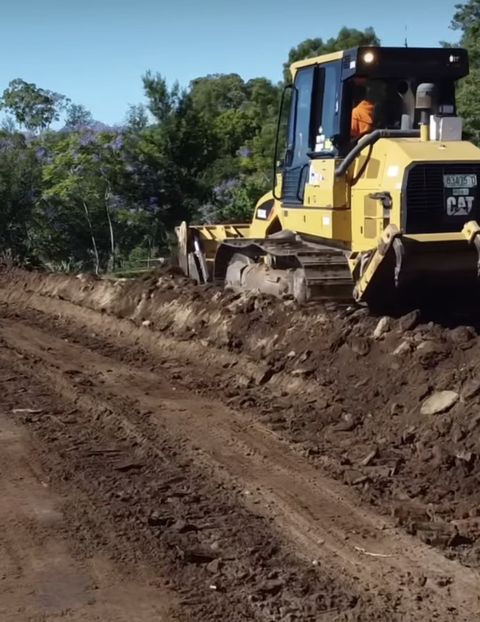 Yellow CAT bulldozer working along a rural earth fire trail, Penrith NSW