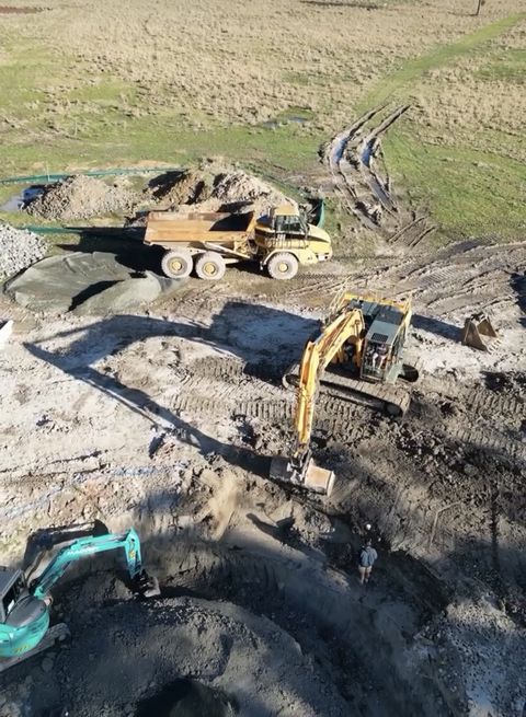 Aerial view of bulk earthworks with dump truck, Hyundai 14t excavator and teal Kobelco loading spoil, Penrith NSW